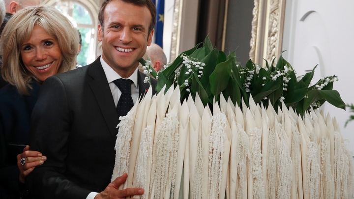 Le président Emmanuel Macron et sa femme Brigitte Macron à côté d'un bouquet de muguet lors d'une cérémonie à l'Elysée où étaient reçus les professionnels des métiers de bouche et des fleurs, le 1er mai 2019 à Paris