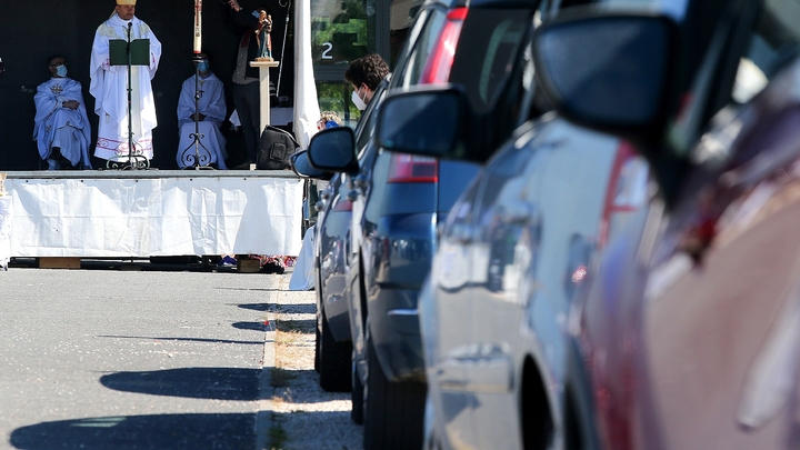 Des automobilistes garés sur un parking assistent à une messe en plein air célébrée par Mgr François Touvet, l'évêque de Châlons-en-Champagne, le 17 mai 2020