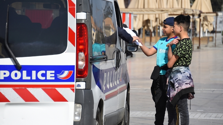 Des policiers contrôlent les attestations de deux adolescents place de la Comédie, le 18 mars 2020 à Montpellier, pendant le confinement instauré en France pour lutter contre le nouveau coronavirus