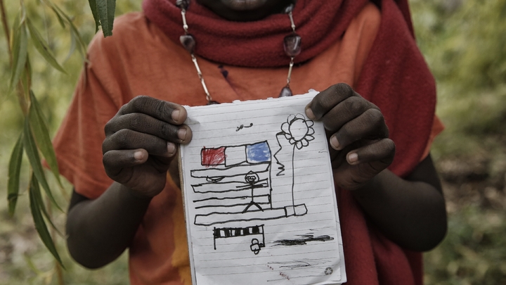 Un enfant montre son dessin dans le jardin de Françoise Cotta, une Française qui accueille des migrants arrivant illégalement en Italie, le 25 octobre 2016 à Breil-sur-Roya, un ancien village franco-italien près de Menton
