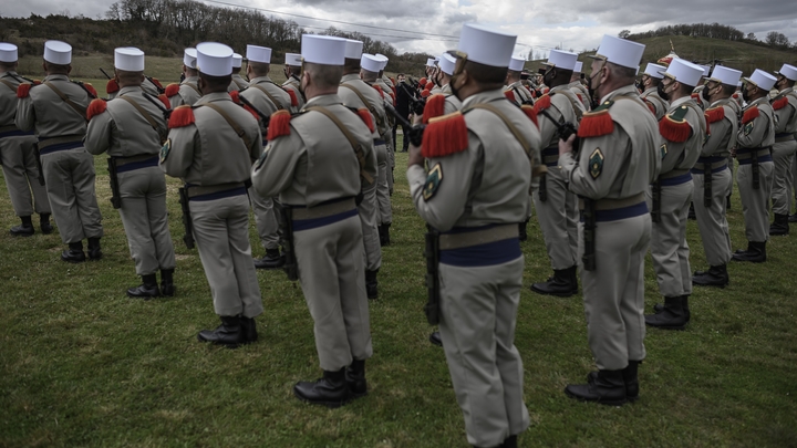 French President Emmanuel Macron reviews soldiers during a military honours ceremony at the Ferme du Cuin