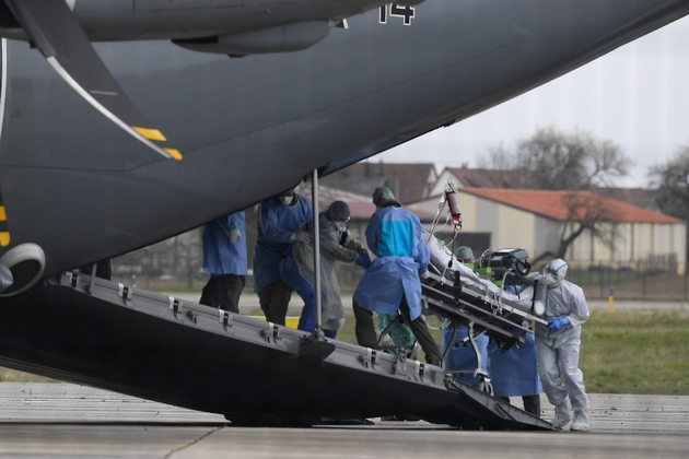 Des membres du  personnel médical transfèrent un patient contaminé par le nouveau coronavirus dans un avion de transport médicalisé allemand Hercules M400 à Strasbourg, le 29 mars 2020 