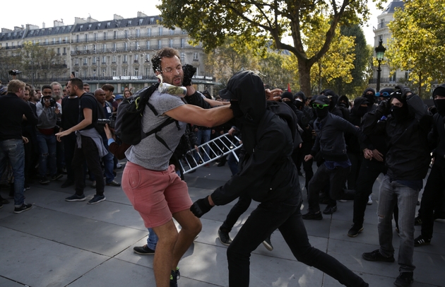 Un manifestant s'interpose face à un groupe de personnes cagoulées qui perturbent la manifestation de la France Insoumise contre les réformes du travail, Place de la République à Paris, le 23 septembre 2017