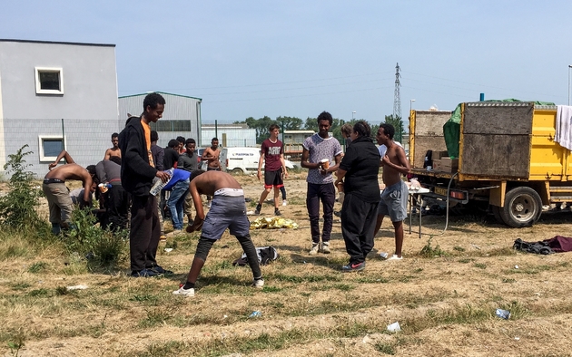 Au coeur de la zone industrielle de Calais (nord), une dizaine d'hommes se débarbouillent, torse nu, le 21 juin 2017