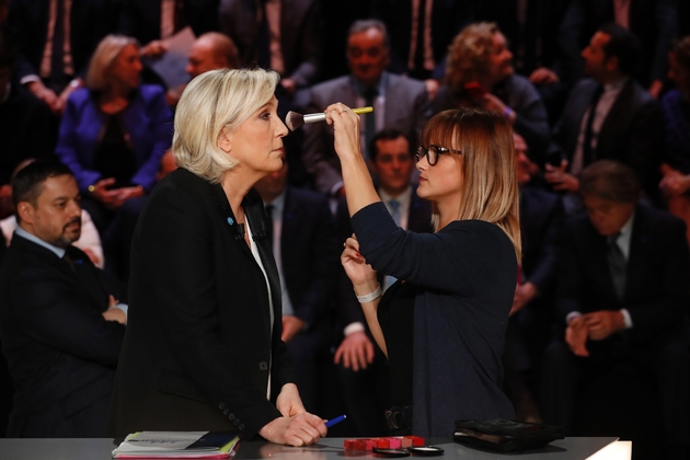 Seule femme parmi les cinq principaux candidats, Marine Le Pen, se distingue avec  une petite rose bleue, logo de sa campagne, qu'elle accroche au revers d'une veste généralement sombre, le 20 mars à Aubervilliers