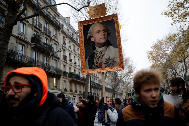 Une femme tient une pancarte représentant Emmanuel Macron en roi de France, lors de la manifestation contre la réforme des retraites le 5 décembre 2019 à Paris