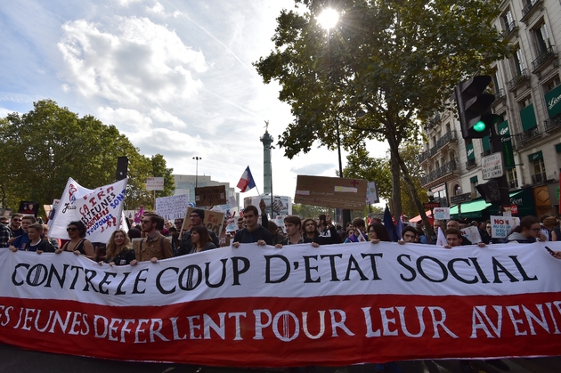 Des manifestants marchent derrière une banderole 