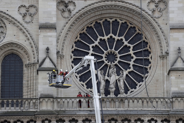 Des pompiers devant l'un des vitraux de la cathédrale Notre Dame de Paris au lendemain de l'incendie qui a ravagé l'édifice, le 16 avril 2019