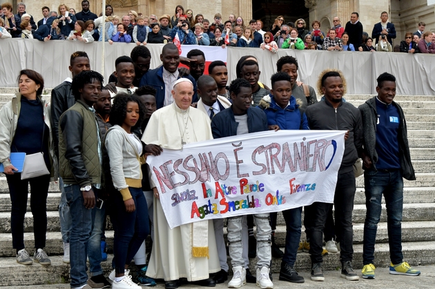 Le pape François pose avec des migrants qui tiennent une banderole sur laquelle est écrit en italien 
