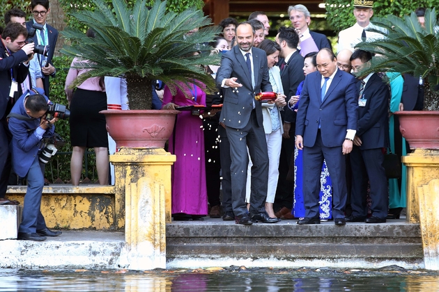 Le Premier ministre français Edouard Philippe (g), aux côtés de son homologue vietnamien Nguyen Xuan Phuc, nourrit des poissons au palais présidentiel, le 2 novembre 2018 à Hanoï