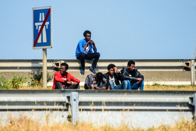 Des migrants attendent le long de la bretelle d'autoroute qui mène aux terminaux du port de Calais (nord), le 21 juin 2017