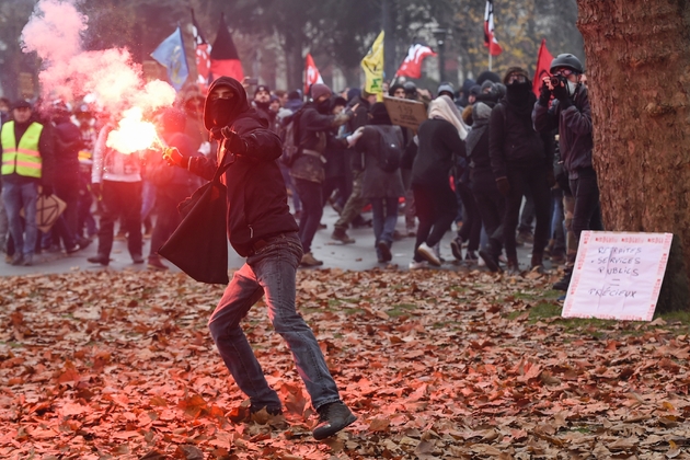 Un manifestant masqué lance un fumigène à Nantes lors d'une manifestation contre la réforme des retraites le 5 décembre 2019
