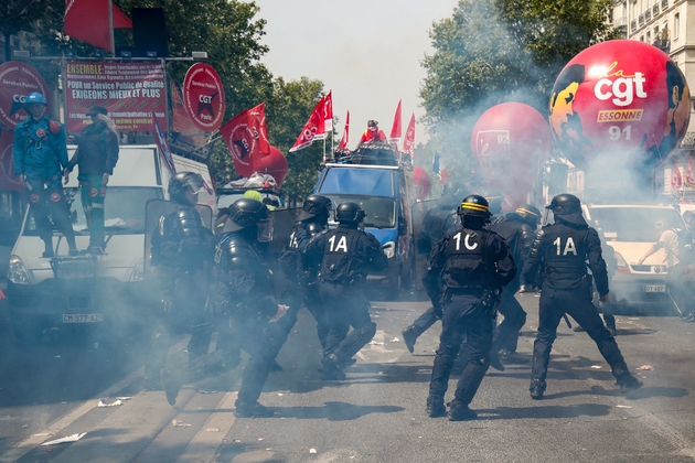 Des policiers passent en courant devant des véhciules de la CGT avant le départ des défilés du 1er mai 2019 à Paris