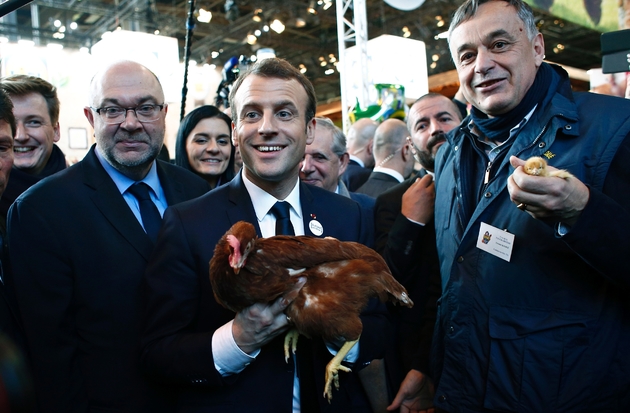 Emmanuel Macron tient une poule offerte par Yves de la Fouchardière (d) président des fermiers de Loué, lors de sa visite au salon de l'Agriculture le 24 février 2018