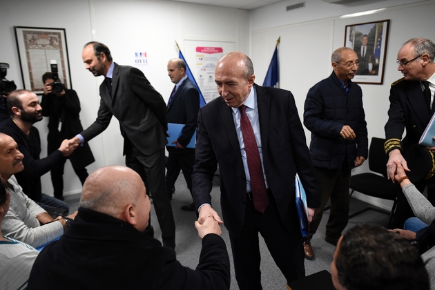 Le ministre de l'Intérieur Gerard Collomb (au centre) serre la main à un réfugié qui a signé un contrat d'intégration républicaine le 19 février 2018 à Lyon