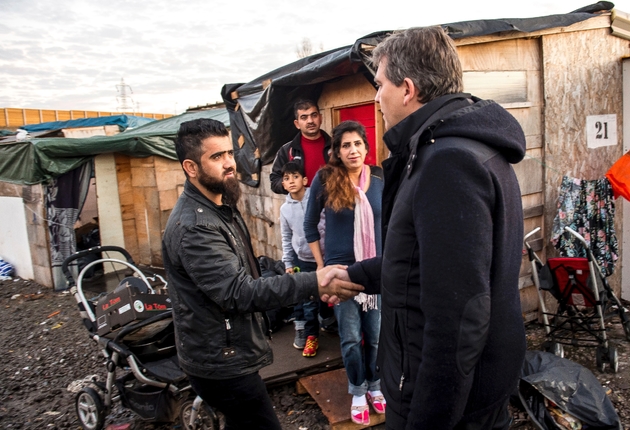 Arnaud Montebourg s'adresse à un réfugié irakien lors de sa visite du camp de réfugiés de  Grande-Synthe (nord de la France), le 14 décembre 2016