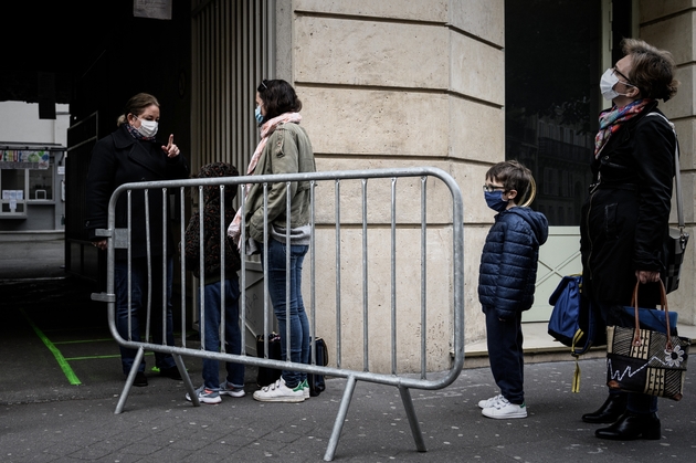 Des parents attendent avec leurs enfants devant l'entrée de l'école, le 12 mai 2020 à Paris