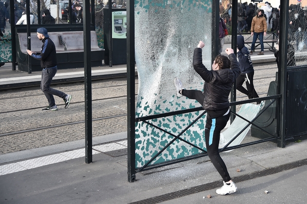 Un manifestant frappe la vitre d'un arrêt de bus lors d'une manifestation contre la venue de Marine Le Pen à Nantes le 27 février 2017