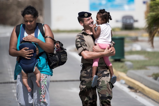 Une famille escortée par un militaire français le 11 septembre 2017 à l'aéroport de Grand-Case Esperance sur l'île française de Saint-Martin frappée par Irma