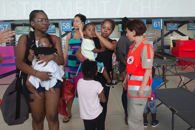 Des membres de la Croix-Rouge aident des familles, évacuées depuis l'île de Saint-Martin ravagée par l'ouragan Irma, à leur arrivée à Pointe-à-Pitre (Guadeloupe)le 9 septembre 2017 