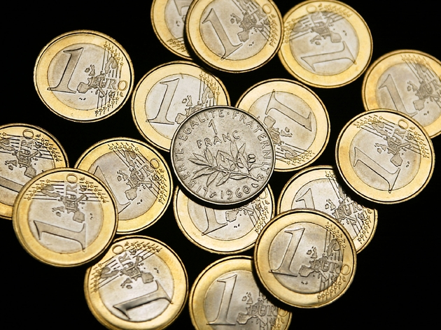 Une pièce de 1 franc entourée de pièces de 1 euro, le 31 décembre 2001 à Paris