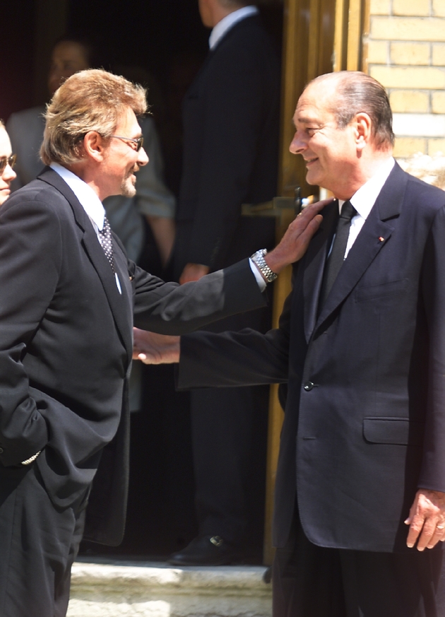 Le chanteur Johnny Hallyday s'entretient le 25 juin 1999 avec le président de la république Jacques Chirac devant l'église Saint-Honoré d'Eylau à Paris à l'occasion des obsèques de la mère de la chanteuse Line Renaud, Simone Boute