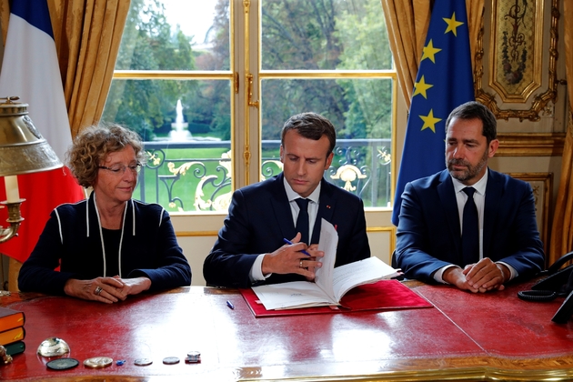 Le président Emmanuel Macron signe les ordonnances réformant le code du travail aux côtés de la ministre du Travail, Muriel Pénicaud, et de Christophe Castaner, porte-parole du gouvernement, le 22 septembre 2017 à l'Elysée