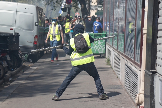 Un manifestant essaye de casser une vitrine durant la manifestation des 