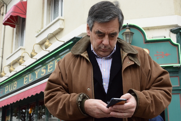 François Fillon regarde son téléphone lors d'un déplacement à Sablé-Sur-Sarthe, le 20 mars 2015