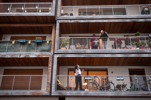des Parisiens, voisins, se parlent de balcon à balcon à Paris le 20 mars 2020.