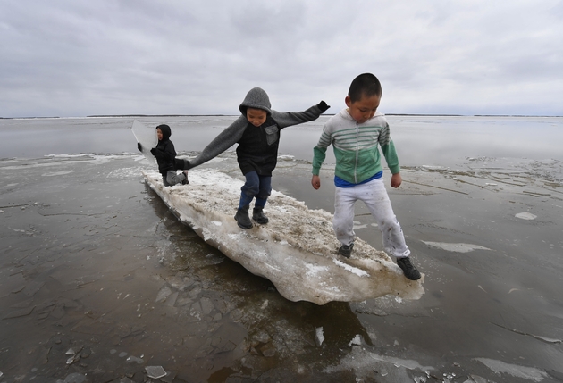 Des enfants jouent sur un morceau de glace près du village eskimau de Yupik, en Alaska (Etats-Unis), le 19 avril 2019