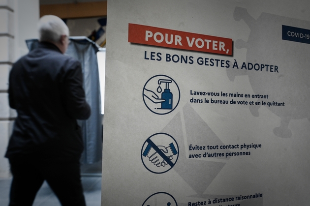 Un votant passe devant une affiche dans un bureau de vote pour le premier tour des élections municipales, le 15 mars 2020 à Paris 