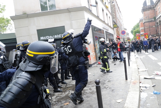 Un CRS lance une grenade lacrymogène contre des manifestants en marge du défilé syndical du 1er mai 2018 à Paris
