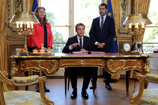 Le président Emmanuel Macron, entouré par la ministre de la Justice Nicole Belloubet et le porte-parole du gouvernement, Christophe Castaner, s'apprête à signer les deux lois de moralisation de la vie politique, le 15 septembre 2017 à l'Elysée, à Paris