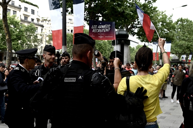 Des gendarmes entourent une jeune femme habillée en jaune criants des slogans anti-Macron, lors du défilé du 14 juillet 2019 sur les Champs-Elysées à Paris