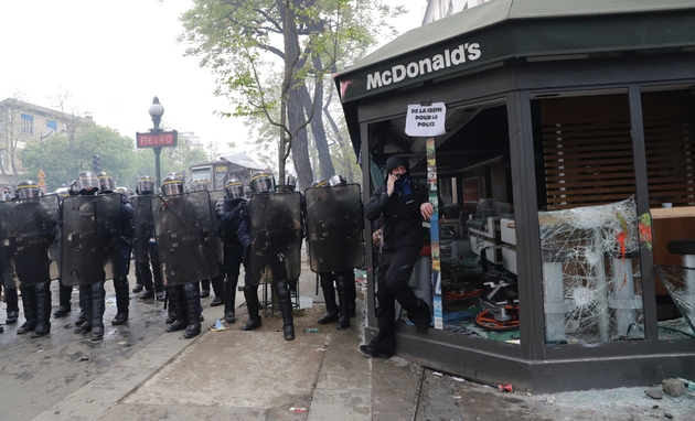Des CRS positionnés à côté d'un restaurant McDonalds dégradé en marge de la manifestation du 1er mai 2018 à Paris