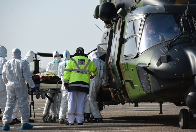 Des équipes médicales transportent un patient contaminé par le Covid-19 pour l'évacuer à bord d'un hélicoptère vers l'hôpital d'Essen, en Allemagne, le 28 mars 2020 sur un parking près du CHR de Metz