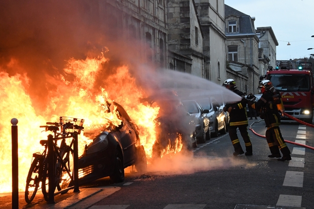 Des pompiers interviennent sur des véhicules incendiés en marge d'une manifestation de 