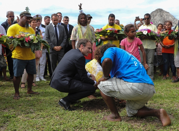 Le président Emmanuel Macron plante un arbre, le 5 mai 2018 à Ouvéa, avec les membres des familles des 19 Kanak tués en 1988 lors de l'assaut de la grotte d'Ouvéa, 